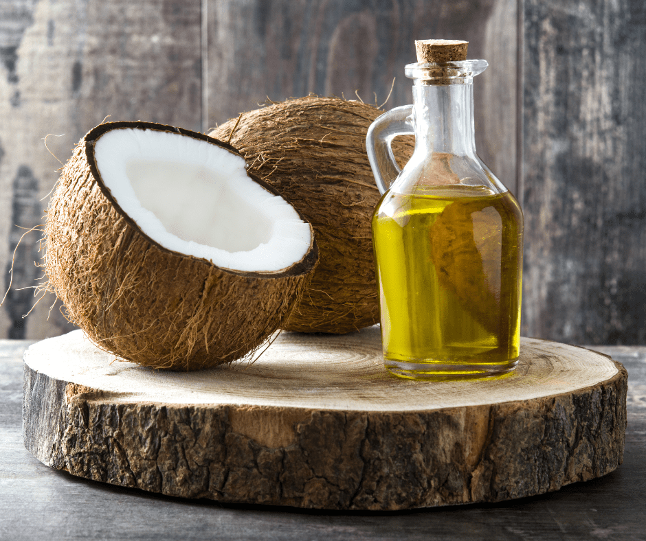 MCT oil, half and whole coconut next to it on tree slice with grey background