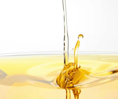 Gelbes Öl welches in Nahaufnahme abgefüllt wird und nach oben spritzt