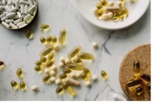 Verschiedene Vitaminkapseln in Schalen und auf einem weißen Tisch