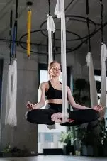 Junge Frau in Sportsachen meditiert in völliger Balance und in der Luft auf Fitnessband